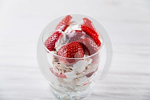 Strawberry dessert in a plate with ice cream and cream on a white wooden background