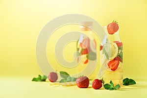 Strawberry detox water with mint, lemon on yellow background. Citrus lemonade. Banner. Summer fruit infused water. Copy photo