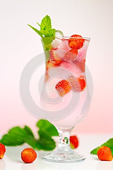 Strawberry drink. summer cocktail.Summer drink.mineral water glass with ice and ripe strawberries with leaves on a light