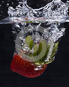 Strawberry dropped in water making a splash.