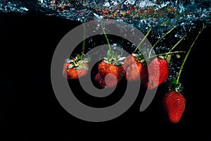 Strawberry dropped into water with splash on black backgro