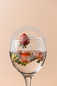 strawberry falling into the balloon cup, the background is salmon-colored