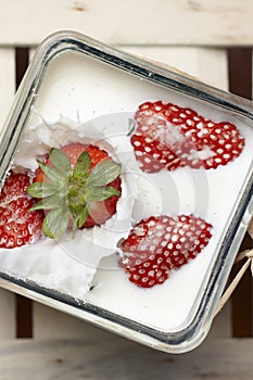 Strawberry falling and splashing into milk