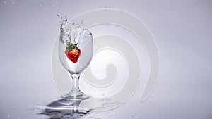 The strawberry falls into a glass of water