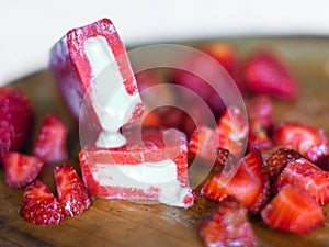 Strawberry-flavored icecreams and fresh strawberries on a wooden board