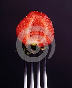 Strawberry on a fork on a black background