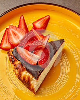 Strawberry garnished cheesecake slice on yellow plate