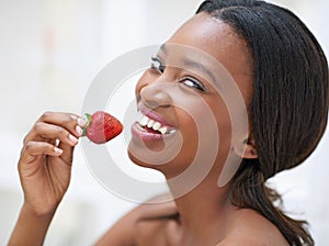 Strawberry giggles. a beautiful young woman eating strawberries.