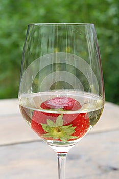 Strawberry in a glass of biological white wine