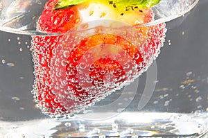 Strawberry in glass of mineral water.