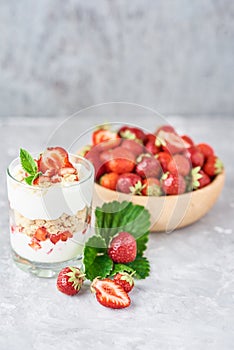 Strawberry granola or smoothie in glass and fresh berries in a wooden bowl. Healthy breakfast