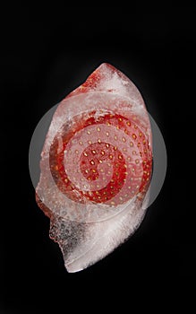 Strawberry in ice on a black