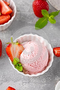 Strawberry ice cream with fresh berries in a bowl on a gray concrete background. Selective focus