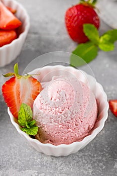 Strawberry ice cream with fresh berries in a bowl on a gray concrete background. Selective focus