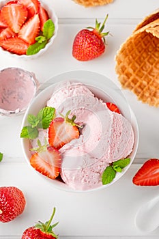 Strawberry ice cream with fresh berries in a bowl on a white wooden background. Selective focus