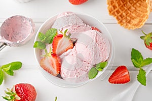 Strawberry ice cream with fresh berries in a bowl on a white wooden background. Selective focus