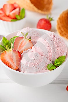 Strawberry ice cream with fresh berries in a bowl on a white wooden background. Selective focus