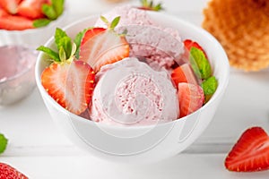 Strawberry ice cream with fresh berries in a bowl on a white wooden background. Selective focus