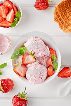 Strawberry ice cream with fresh berries in a bowl on a white wooden background. Selective focus