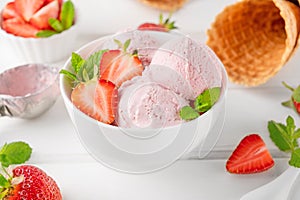 Strawberry ice cream with fresh berries in a bowl on a white wooden background. Selective focus