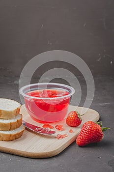 Strawberry jam. Bread and strawberry jam on a dark stone background with jar of jam and fresh strawberry. Making sandwiches with