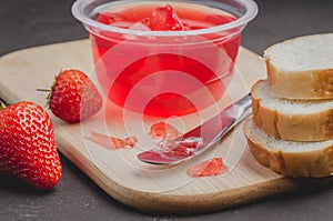 Strawberry jam. Bread and strawberry jam on a dark stone background with jar of jam and fresh strawberry. Making sandwiches with