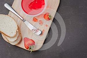 Strawberry jam. Bread and strawberry jam on a dark stone background with jar of jam and fresh strawberry. Top view, copyspace.