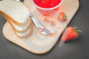 Strawberry jam. Bread and strawberry jam on a dark stone background with jar of jam and fresh strawberry. Top view. Making