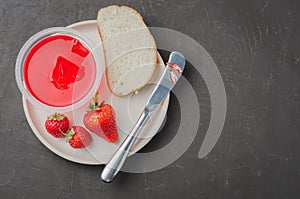 Strawberry jam. Bread and strawberry jam on a dark stone background with jar of jam and fresh strawberry. Top view. Making