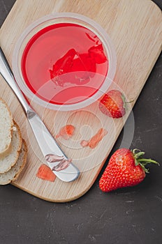 Strawberry jam. Bread and strawberry jam on a dark stone background with jar of jam and fresh strawberry. Top view. Making