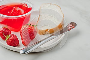 Strawberry jam. Bread and strawberry jam on a white table with jar of jam and fresh strawberry