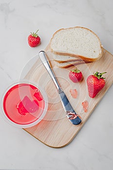 Strawberry jam. Bread and strawberry jam on a wooden table with jar of jam and fresh strawberry. Making sandwiches with strawberry