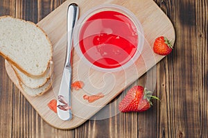 Strawberry jam. Bread and strawberry jam on a wooden table with jar of jam and fresh strawberry. Top view. Making sandwiches with