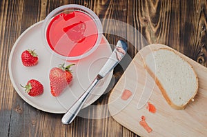 Strawberry jam. Bread and strawberry jam on a wooden table with jar of jam and fresh strawberry. Top view. Making sandwiches with