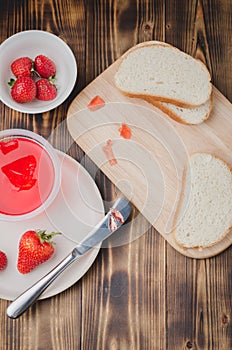 Strawberry jam. Bread and strawberry jam on a wooden table with jar of jam and fresh strawberry. Top view. Making sandwiches with