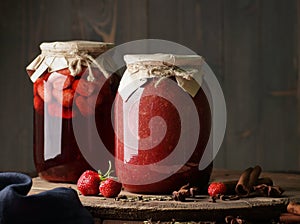 Strawberry jam in glass can with fresh berry and leaf on wood and rustic background, cottagecore aesthetic