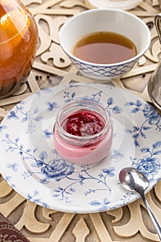 Strawberry jam in a jar and cup of black tea on oriental wooden table