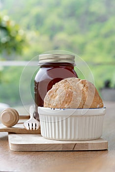 Strawberry jam in jar and fresh homemade bread on wood background