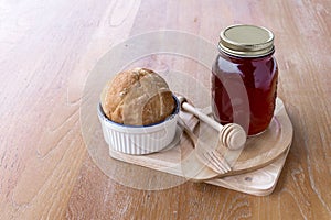 Strawberry jam in jar and fresh homemade bread on wood background