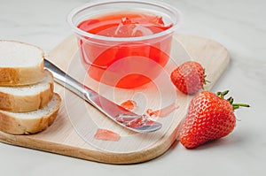 Strawberry jam. Making sandwiches with strawberry jam. Bread and strawberry jam on a white table with jar of jam and fresh