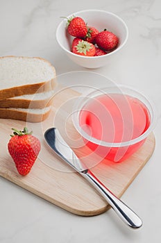 Strawberry jam. Making sandwiches with strawberry jam. Bread and strawberry jam on a white table with jar of jam and fresh