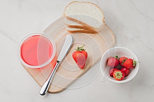 Strawberry jam. Making sandwiches with strawberry jam. Top view. Bread and strawberry jam on a white table with jar of jam and