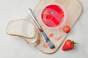 Strawberry jam. Making sandwiches with strawberry jam. Top view. Bread and strawberry jam on a white table with jar of jam and