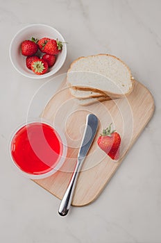 Strawberry jam. Making sandwiches with strawberry jam. Top view. Bread and strawberry jam on a white table with jar of jam and