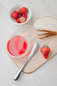 Strawberry jam. Making sandwiches with strawberry jam. Top view. Bread and strawberry jam on a white table with jar of jam and