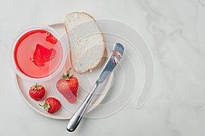 Strawberry jam. Making sandwiches with strawberry jam. Top view, copyspace. Bread and strawberry jam on a white table with jar of