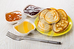 Strawberry jam, peach jam, honey, homemade pancakes in saucer, f