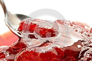 Strawberry jam is stirred with a spoon on a white background. Fruit dessert close up. Confectionery
