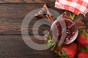 Strawberry jam. Strawberry jam in glass jar with fresh berries plate on an old wooden dark table background, closeup. Homemade str