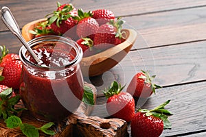 Strawberry jam. Strawberry jam in glass jar with fresh berries plate on an old wooden dark table background, closeup. Homemade str